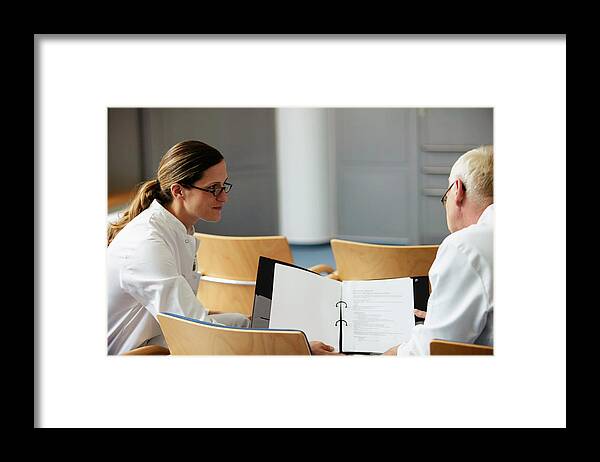 Expertise Framed Print featuring the photograph Female doctor showing notes to male colleague by Jochen Sand