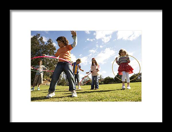 Grass Framed Print featuring the photograph Five children (7-12) playing with plastic hoops in park by Bec Parsons