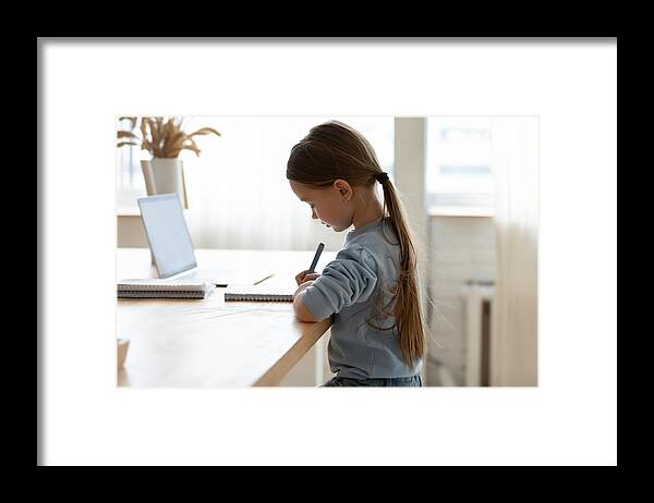 White People Framed Print featuring the photograph Focused small adorable caucasian girl preparing homework alone. by Fizkes