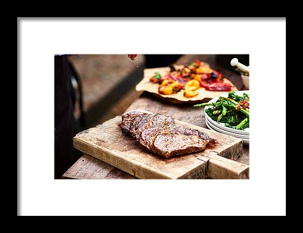 Sprinkling Framed Print featuring the photograph Freshly cooked steak on wooden board with salt flakes by 10'000 Hours