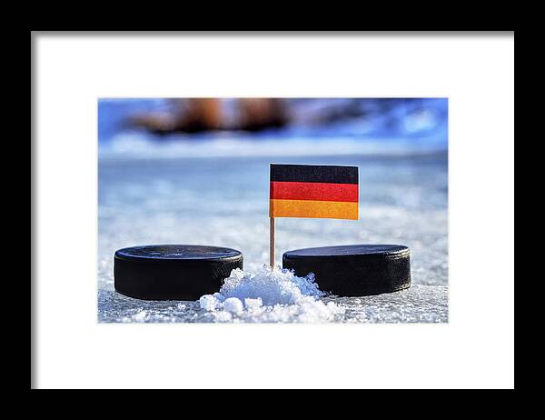 Germany Framed Print featuring the photograph Germany flag on toothpick between two hockey pucks. Winter classic. Flag on frozen pond on unkempt ice. Traditional pucks for international matches. by Vaclav Sonnek