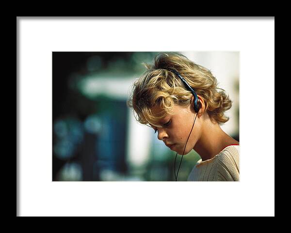 Child Framed Print featuring the photograph Girl listening to headphones by Laurence Mouton