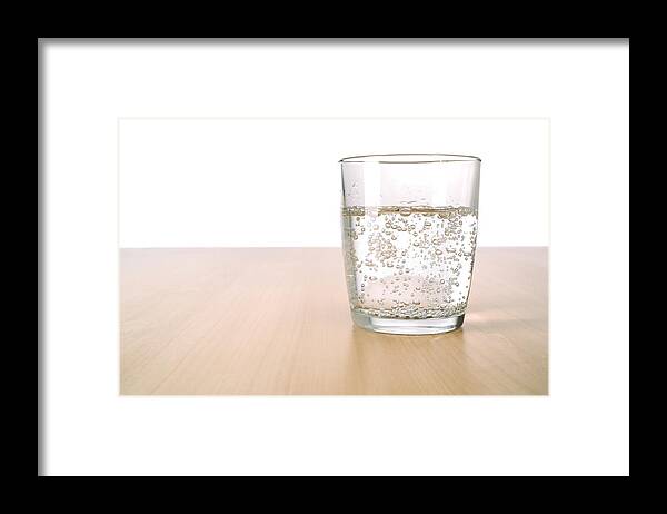 Purified Water Framed Print featuring the photograph Glass of sparkling water on table by Stockcam