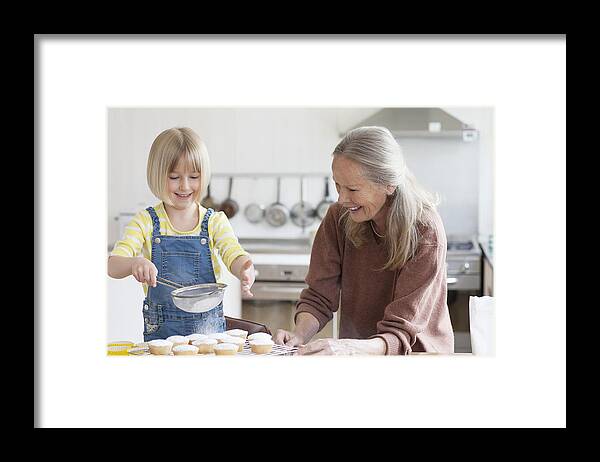 Sweater Framed Print featuring the photograph Granddaughter and grandmother baking cakes by Compassionate Eye Foundation/Natasha Alipour Faridani