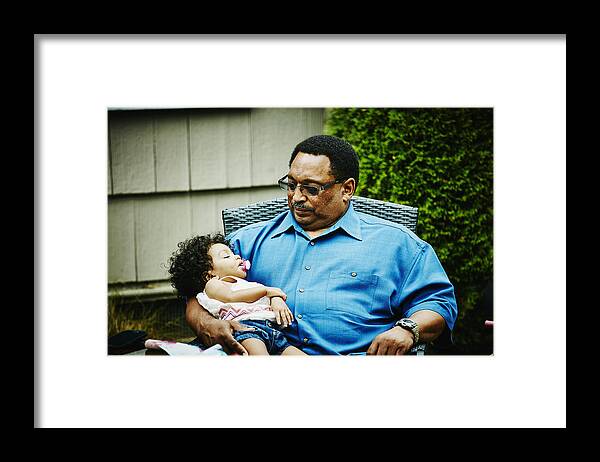 Babyhood Framed Print featuring the photograph Grandfather holding sleeping toddler granddaughter by Thomas Barwick