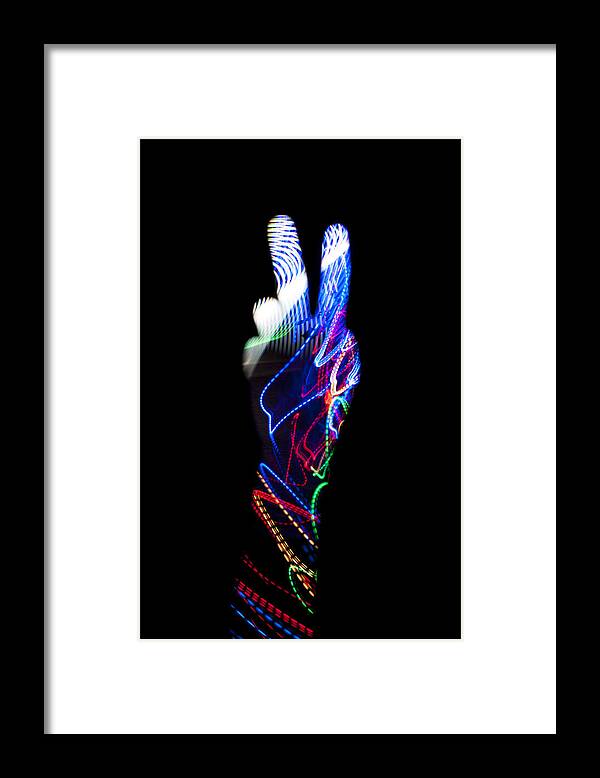 Black Background Framed Print featuring the photograph Hand with light trail making V for victory sign by Colormos