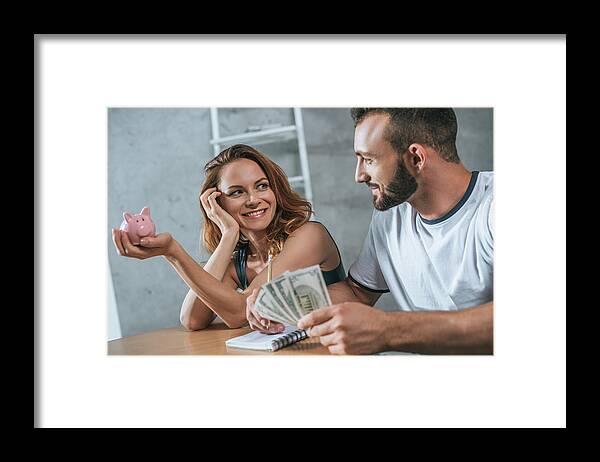 Strategy Framed Print featuring the photograph Happy Couple Planning Family Budget And Looking At Each Other In Living Room by LightFieldStudios