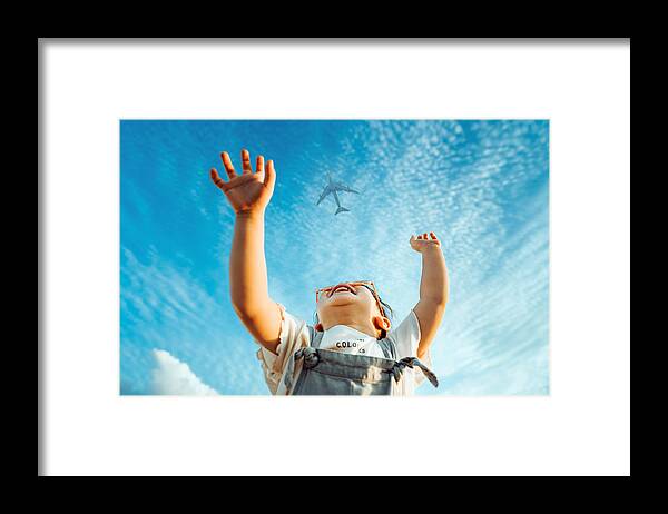 Toddler Framed Print featuring the photograph Happy little Asian girl with flower-shaped sunglasses smiling joyfully and raised her hands waving to the aeroplane in the clear blue sky by D3sign