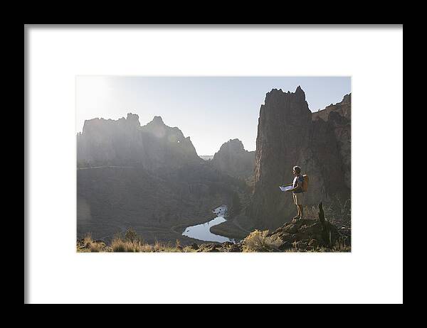 Mature Adult Framed Print featuring the photograph Hiker consults trail map, looks out to mtns, river by Ascent/PKS Media Inc.