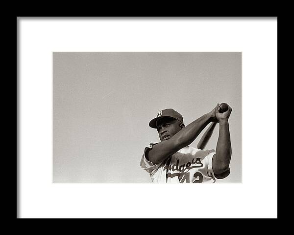 Jackie Robinson in Brooklyn Dodgers uniform, swinging bat Framed