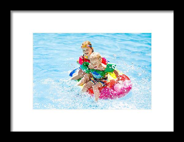 Preschool Student Framed Print featuring the photograph Kids on inflatable float in swimming pool. by FamVeld