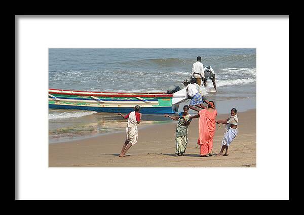 Working Framed Print featuring the photograph Local fishermen push their fishing boats ashore in Gokarna, Karnataka, India by Photo by Victor Ovies Arenas