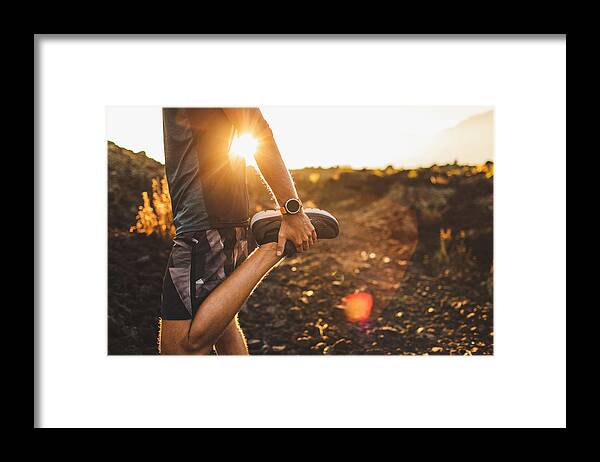 Scenics Framed Print featuring the photograph Male runner stretching leg and feet and preparing for running outdoors. Smart watch or fitness tracker on hand. Beautiful sun light on background. Active and healthy lifestyle concept. by Olegbreslavtsev