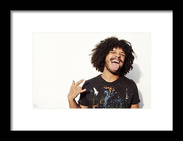 Rock Music Framed Print featuring the photograph Mixed race man making a face and rock-on hand gesture by Granger Wootz