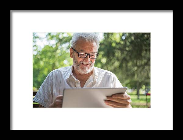 Working Framed Print featuring the photograph Modern senior man with tablet by Freemixer