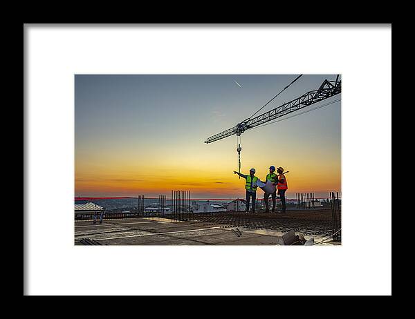 Expertise Framed Print featuring the photograph Multi ethic workers talking at construction site reviewing plans by Ljubaphoto