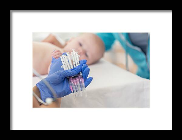 Child Framed Print featuring the photograph Pediatric nurse holds many syringes during baby's well check appointment by SDI Productions