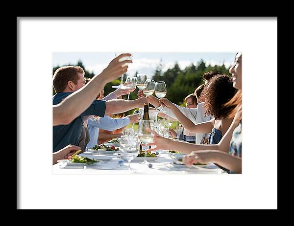 Young Men Framed Print featuring the photograph People toasting wine glasses at outdoor dinner party by Image Source