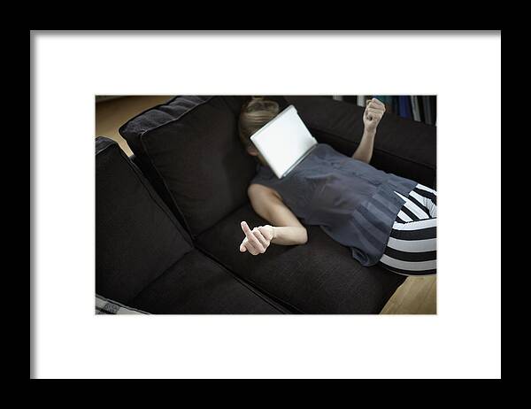 Three Quarter Length Framed Print featuring the photograph Playful young woman on couch with digital tablet by Oliver Rossi