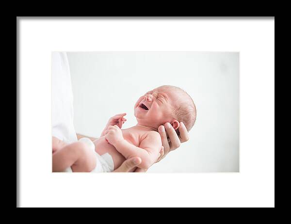 Care Framed Print featuring the photograph Portrait of a screaming newborn hold at hands by Fizkes