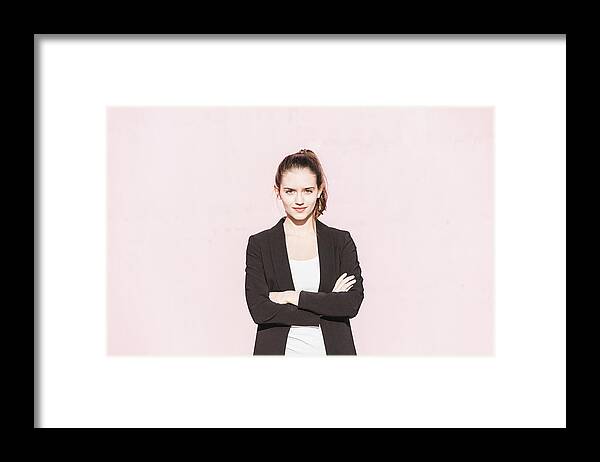 People Framed Print featuring the photograph Portrait of confident young woman in front of pink wall by Westend61