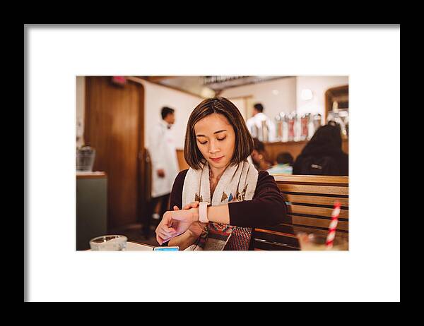 People Framed Print featuring the photograph Pretty young lady waiting and using her smartwatch joyfully in the restaurant by Images By Tang Ming Tung