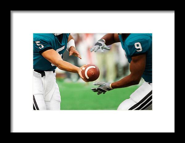 American Football Uniform Framed Print featuring the photograph Quarterback handing off football to running back, mid section by David Madison