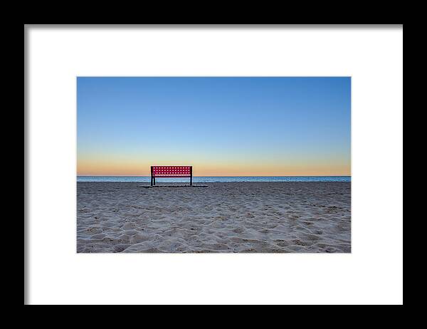 Seascape Framed Print featuring the photograph Red empty bench at the beach at sunset, sand in foreground and ocean in backround by Finn Bjurvoll Hansen