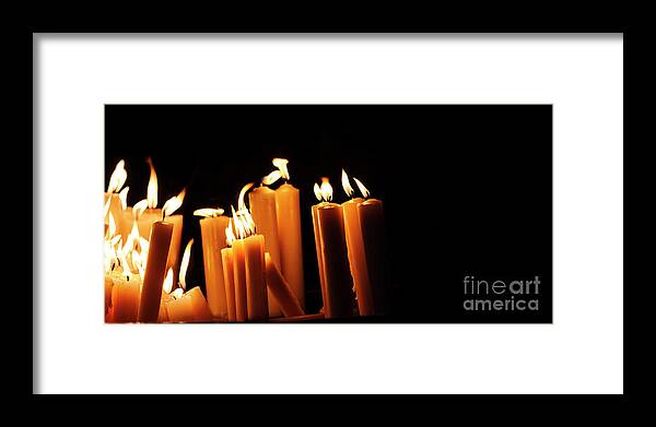 Candle Framed Print featuring the photograph Religious candles on black background. Yellow candlelight f by Jelena Jovanovic