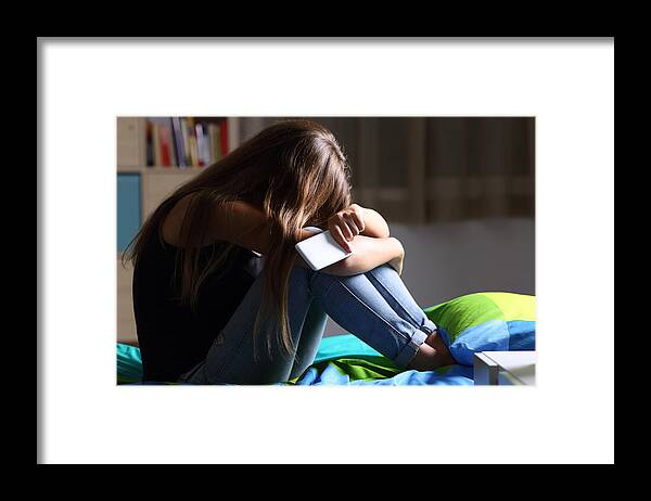 Problems Framed Print featuring the photograph Sad teen with a phone in her bedroom by AntonioGuillem