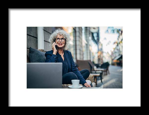 Mature Adult Framed Print featuring the photograph Senior lady talking on mobile outdoors in cafe by South_agency