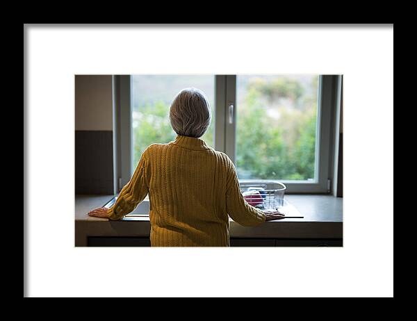 Apartment Framed Print featuring the photograph Senior woman standing near the kitchen sink and looking through window by Wavebreakmedia