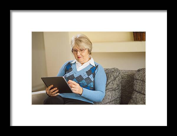 Internet Framed Print featuring the photograph Senior woman using digital tablet at home by EmirMemedovski