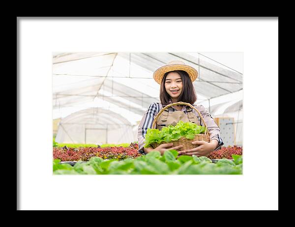 Working Framed Print featuring the photograph Shot of a young woman holding a crate full of freshly picked produce on a farm by Jub Rubjob
