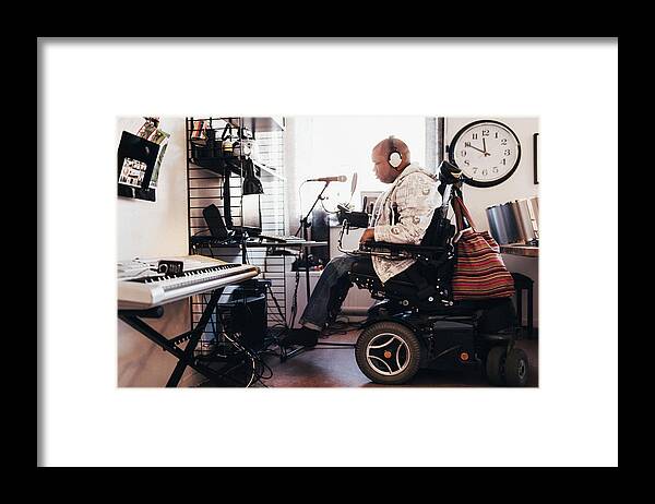 Working Framed Print featuring the photograph Side view of disabled musician with headphones in recording studio by Maskot