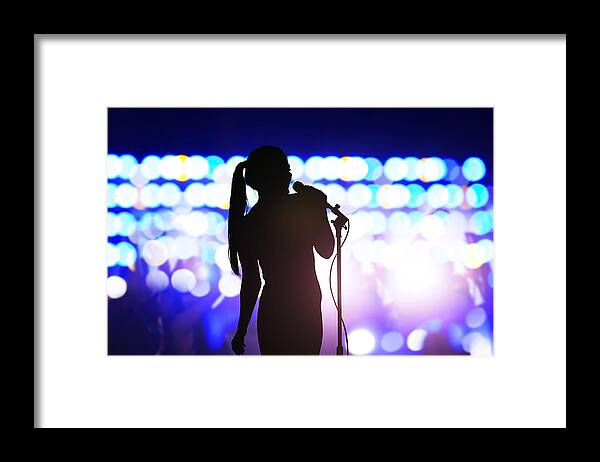 Cool Attitude Framed Print featuring the photograph Silhouette of woman with microphone singing on concert stage in front of crowd by FangXiaNuo