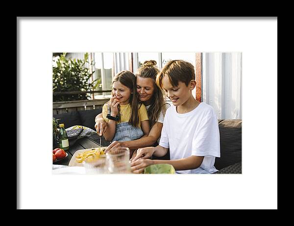 Sibling Framed Print featuring the photograph Smiling mother cutting vegetable on table in balcony by Maskot