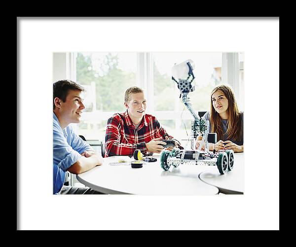 Education Framed Print featuring the photograph Student using remote control to operate robot by Thomas Barwick