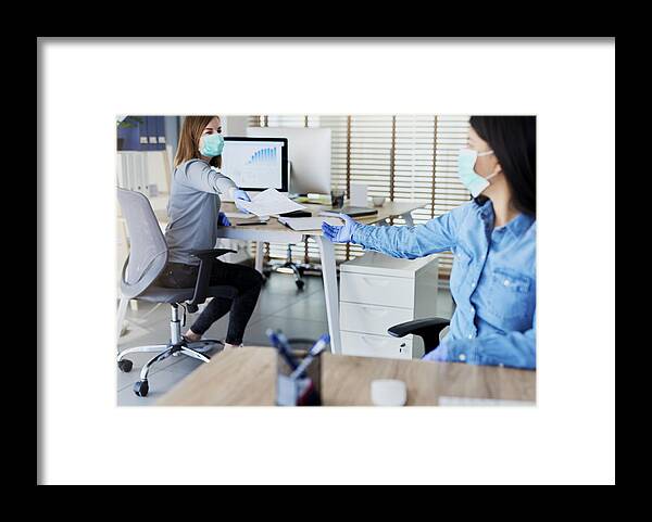 Working Framed Print featuring the photograph Two people in office passing documents with keeping a distance by Gpointstudio