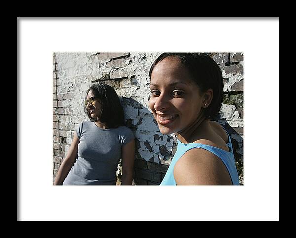 Outdoors Framed Print featuring the photograph Two Young Women Are Standing Against An Old Brick Wall by Photodisc