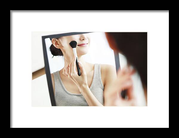 People Framed Print featuring the photograph Woman applying blush in mirror by Runstudio