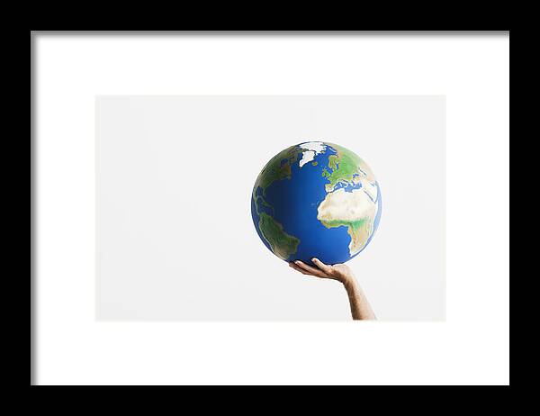 Artificial Framed Print featuring the photograph Woman holding globe in raised hands against white background, close-up by Martin Barraud