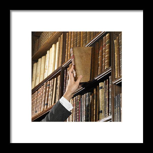 Rack Framed Print featuring the photograph Woman reaching for book in library by Dougal Waters