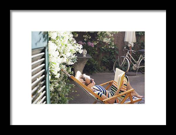 Tranquility Framed Print featuring the photograph Woman relaxing on deck chair in backyard, reading a book by Kathrin Ziegler
