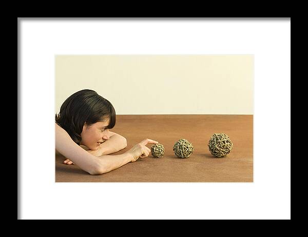 Human Arm Framed Print featuring the photograph Woman resting head on arms, looking at balls of string, side view by ZenShui/Milena Boniek