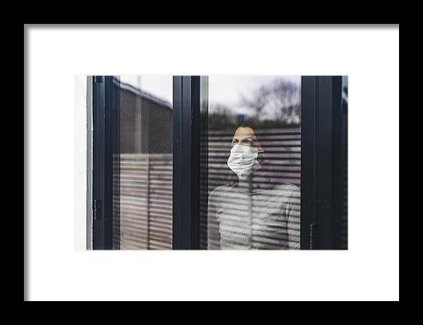 Cold And Flu Framed Print featuring the photograph Woman with mask looking out of window by Justin Paget