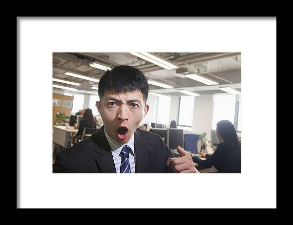 Young Men Framed Print featuring the photograph Young Businessman pointing and shouting, looking at camera by XiXinXing