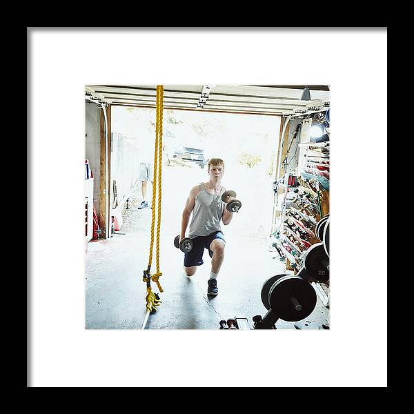 Young Men Framed Print featuring the photograph Young man doing lunges with dumbbells in gym in garage by Thomas Barwick