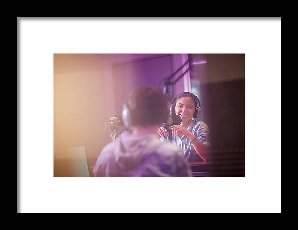 Form Of Communication Framed Print featuring the photograph Young woman and man broadcasting in recording studio by Zero Creatives