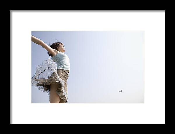 Wind Framed Print featuring the photograph Young woman jumping in air outdoors, arms outstretched by Yasuhide Fumoto
